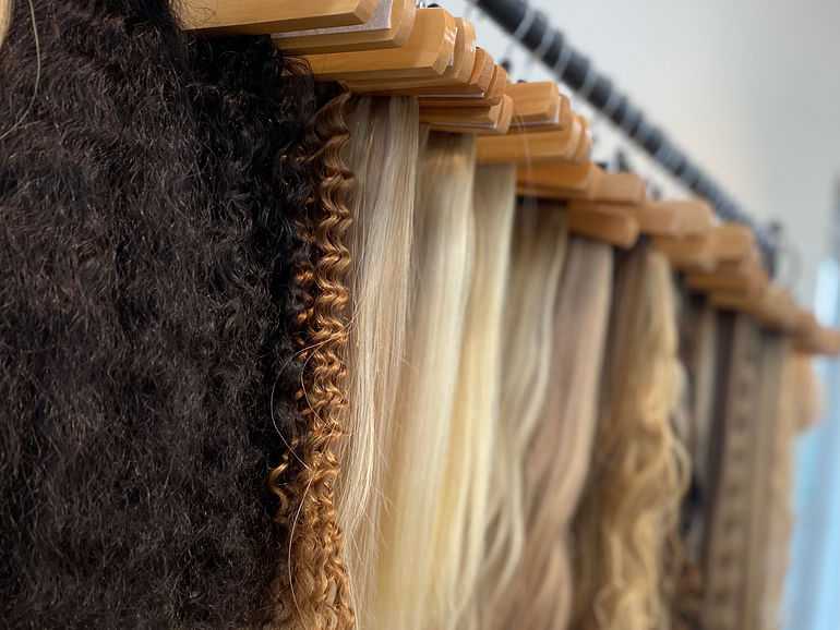 Various hair extensions displayed on hangers in a store.