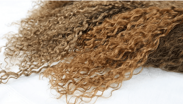 Close-up of various shades of curly hair extensions.