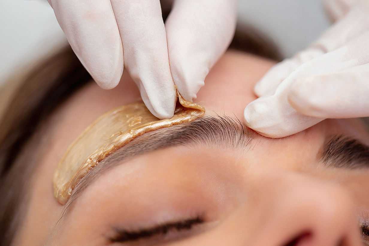 Applying a brown facial mask on a woman's forehead at a spa.