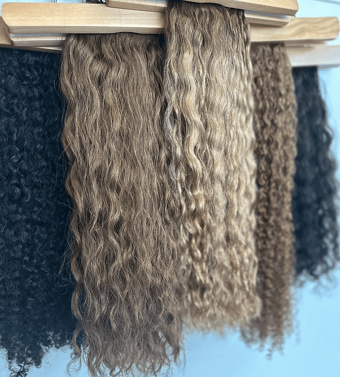 Four different types of curly hair extensions displayed on hangers.