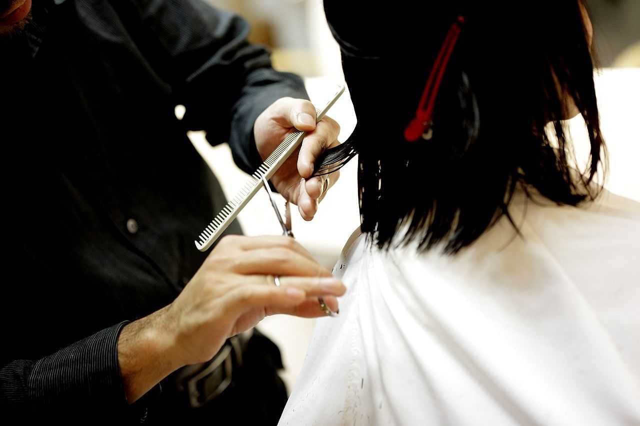 Hairdresser trimming a client's hair with scissors and comb.